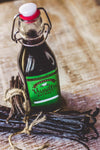Bottle of vanilla extract with vanilla beans on a wooden surface