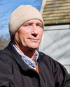 Man wearing a beige beanie and dark jacket outdoors