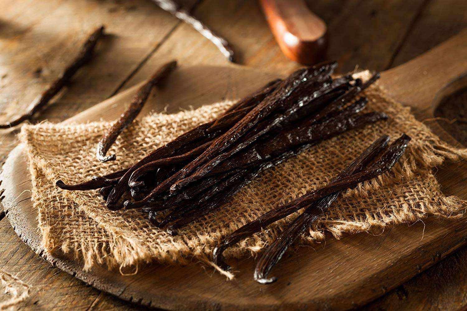 Vanilla beans on a wooden surface with burlap cloth