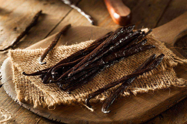 Vanilla beans on a wooden surface with burlap cloth