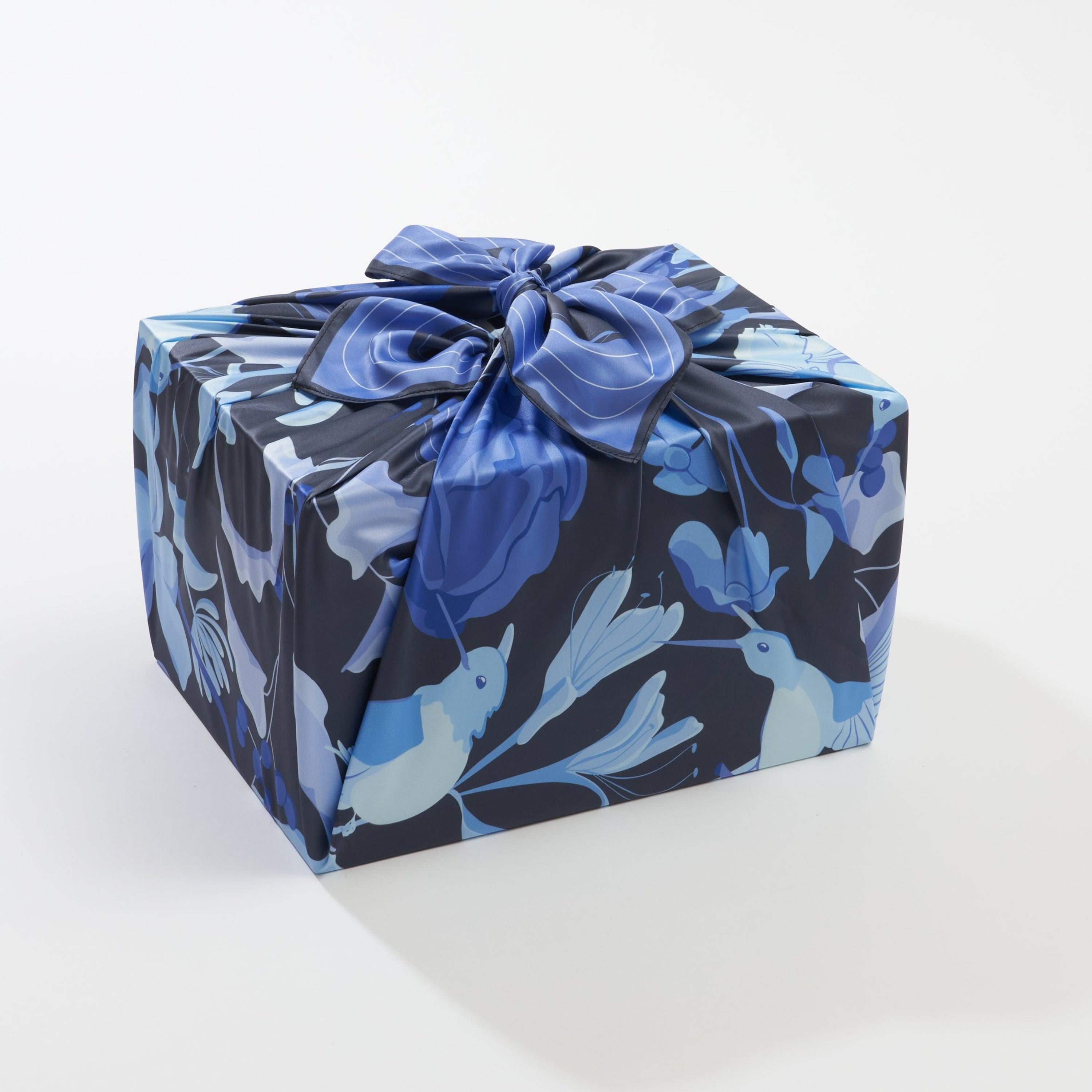 Gift box wrapped in blue floral paper with a bow on a white background