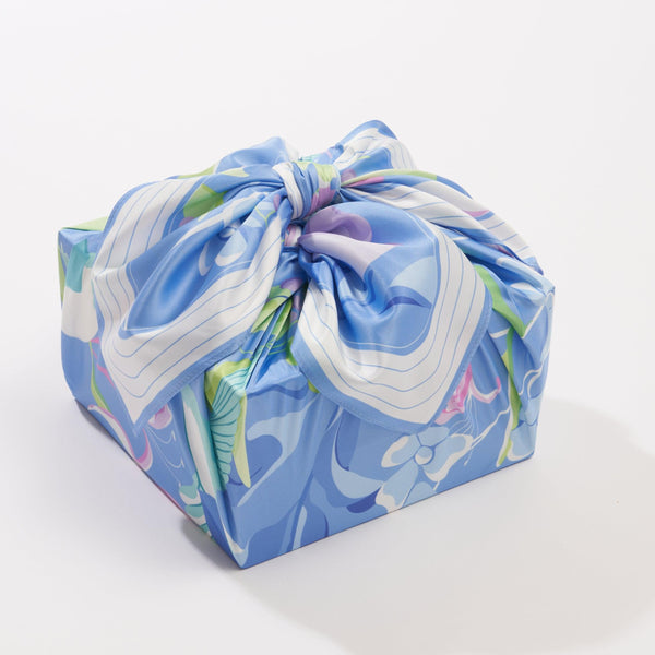 Decorative package wrapped in blue floral fabric with a bow on a white background