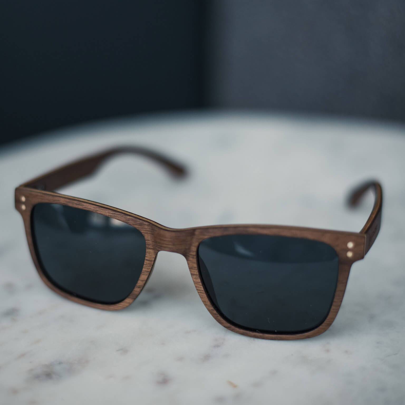 Walnut Wayfinder unisex wooden sunglasses with American walnut frames on a flat lay surface