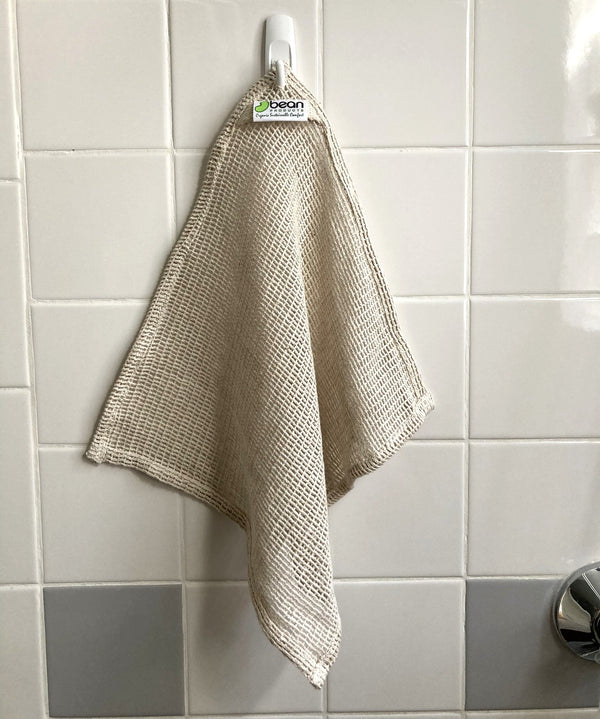 Beige dishcloth hanging on a hook against a tiled wall