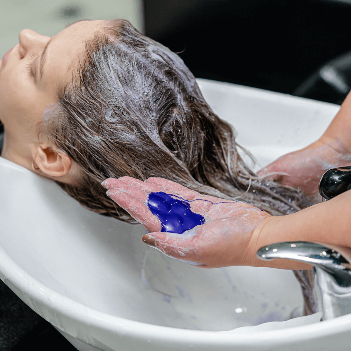 Person washing hair with purple toning shampoo to remove brassiness