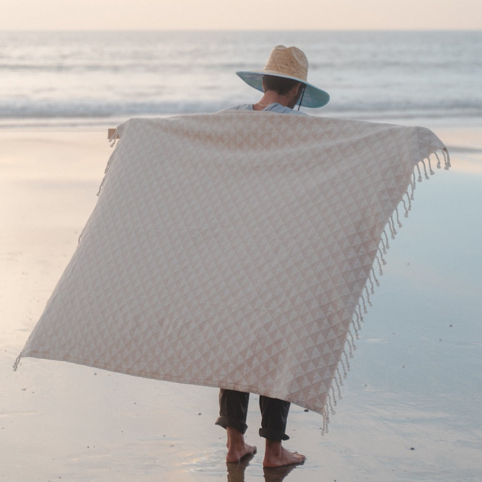 Person on a beach with a large patterned towel draped over them