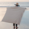 Person on a beach with a large patterned towel draped over them
