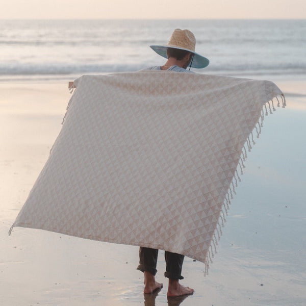 Person on a beach with a large patterned towel draped over them