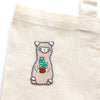 Embroidered llama holding a cactus on a beige fabric background