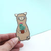 Embroidered patch of a llama holding a cactus on a light blue background