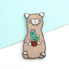 Embroidered patch of a llama holding a cactus on a light blue and white background
