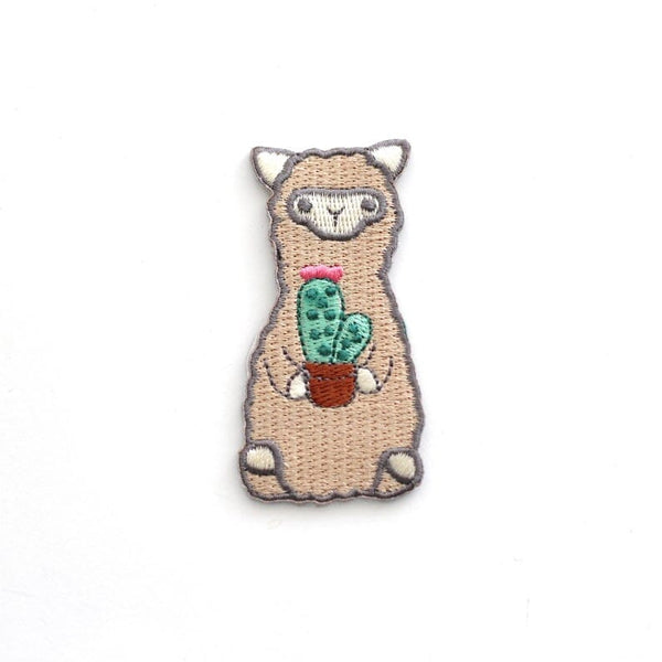 Embroidered patch of a llama holding a cactus on a white background