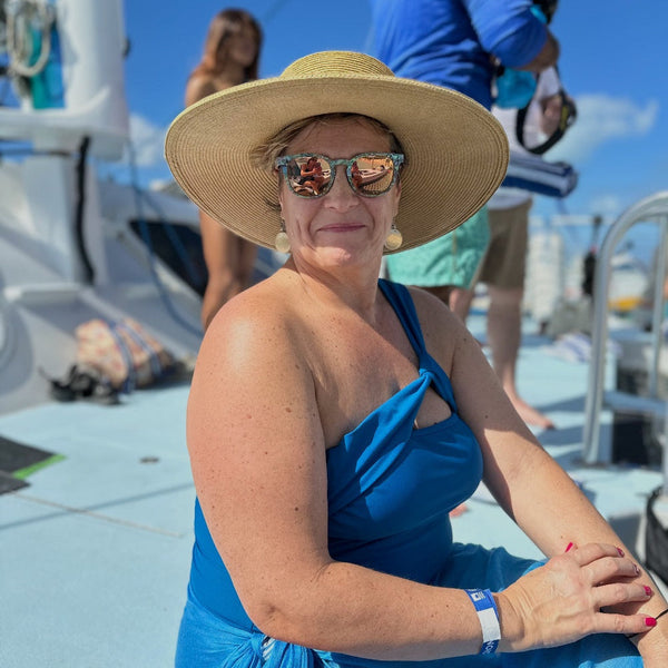 Woman wearing AquaWave square wooden sunglasses with hat outdoors in natural light