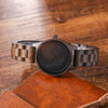 Wooden watch with dark face on a wooden surface