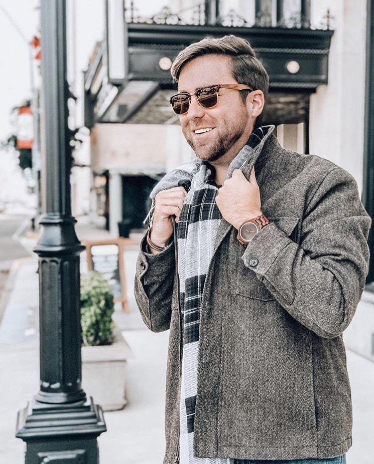 Man wearing sunglasses and a gray coat on a city street