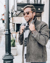 Man wearing sunglasses and a gray coat on a city street