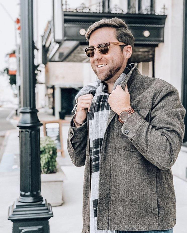 Man wearing sunglasses and a gray coat on a city street