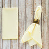 Yellow napkin with a gold napkin ring on a wooden surface