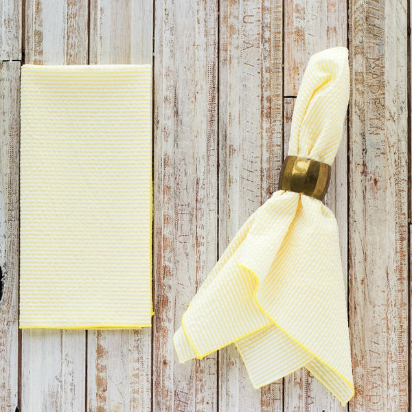Yellow napkin with a gold napkin ring on a wooden surface