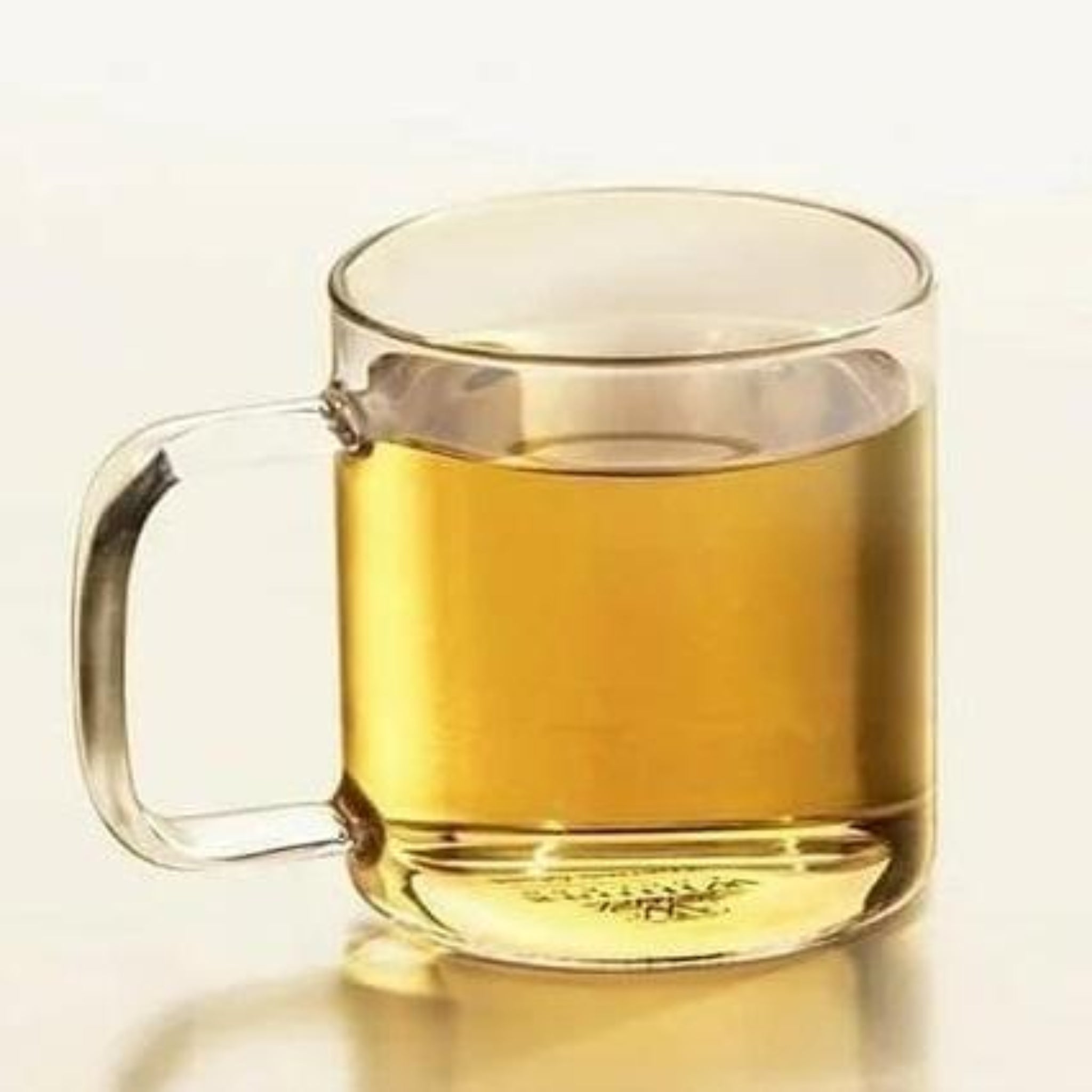 A clear glass cup filled with a yellow beverage, showcasing its transparency and cylindrical shape with a handle.