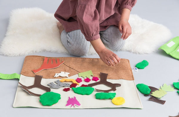 A photo of a child playing with the Forest Habitat Storyboard set and exploring the different animals and plants